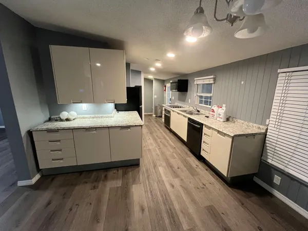 a large white kitchen with a stove a sink dishwasher and a oven with wooden floor