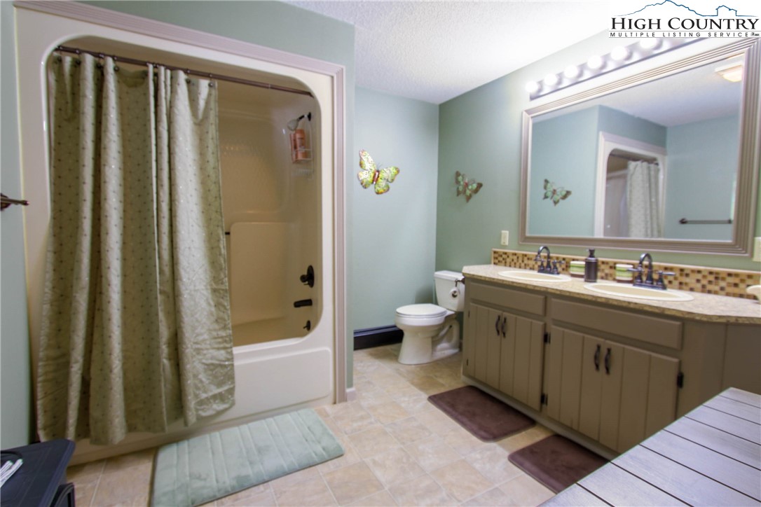 581 North Fork New River Road Lansing, NC 28643 - Photo 33 of 44 a spacious bathroom with a double vanity sink a mirror a bathtub and shower