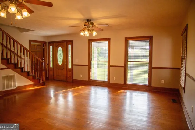 a view of an empty room with wooden floor and a window