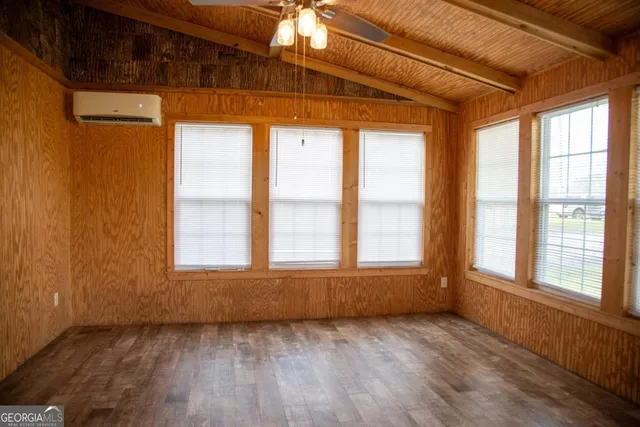 a view of an empty room with a window and wooden floor