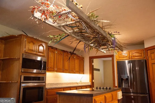 a kitchen with stainless steel appliances kitchen island granite countertop a refrigerator and a stove top oven