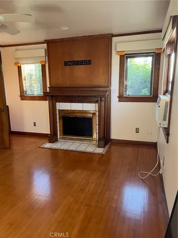 an empty room with wooden floor fireplace and windows