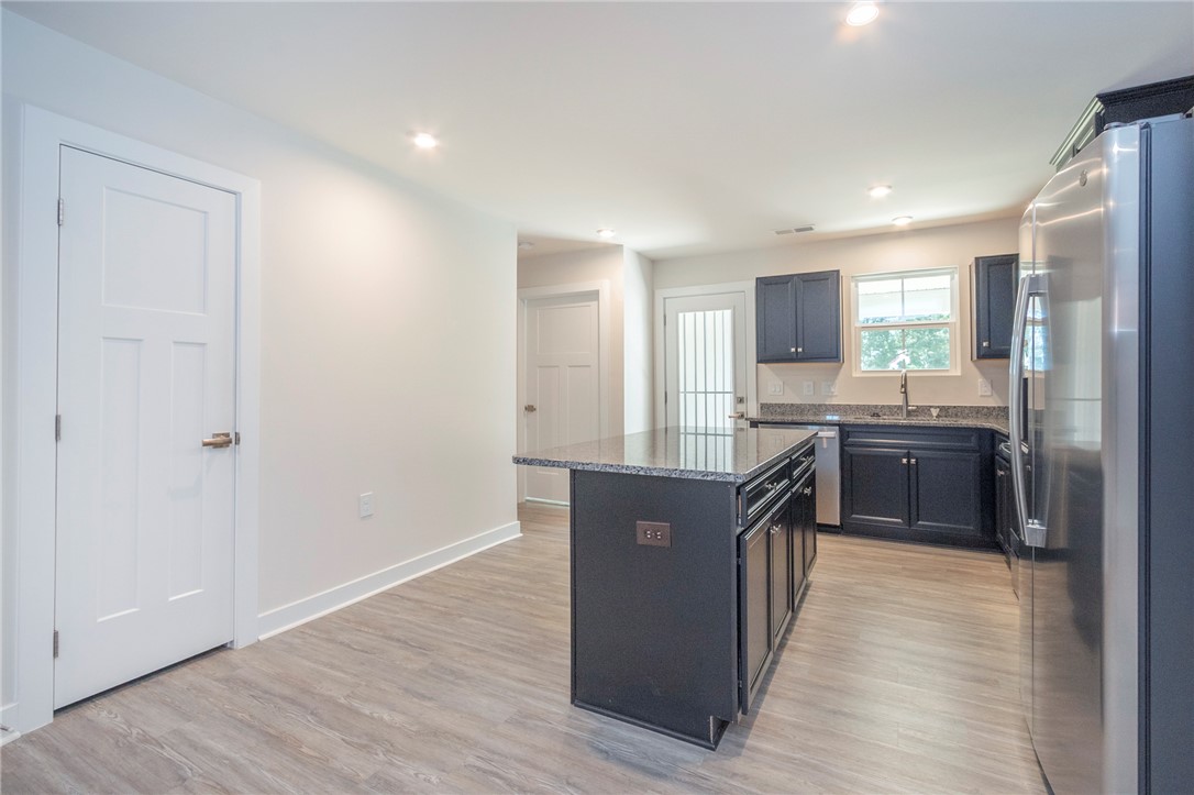 233 Scenic Road Anderson, SC 29621 - Photo 11 of 50 A contemporary kitchen showcasing dark cabinetry, granite countertops, and sleek stainless steel appliances.
