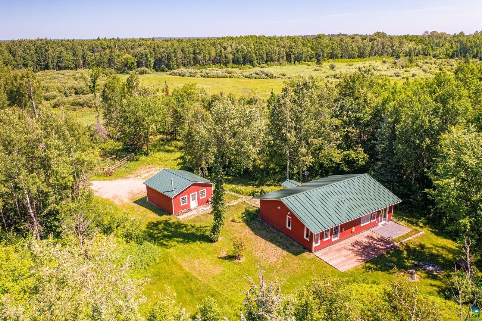 9734 Alango Road Angora, MN 55703 - Photo 32 of 41 Red-sided main residence with a green metal roof, accompanied by a detached red-sided auxiliary building with a matching green metal roof