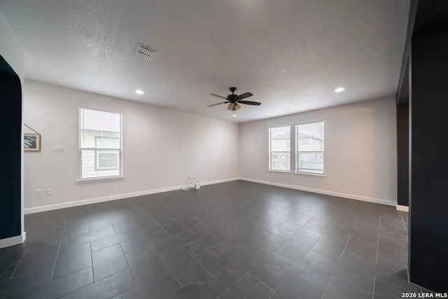 an empty room with windows and ceiling fan