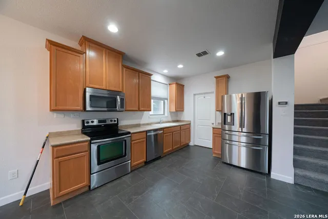 a kitchen with stainless steel appliances granite countertop a refrigerator a stove a sink and a microwave