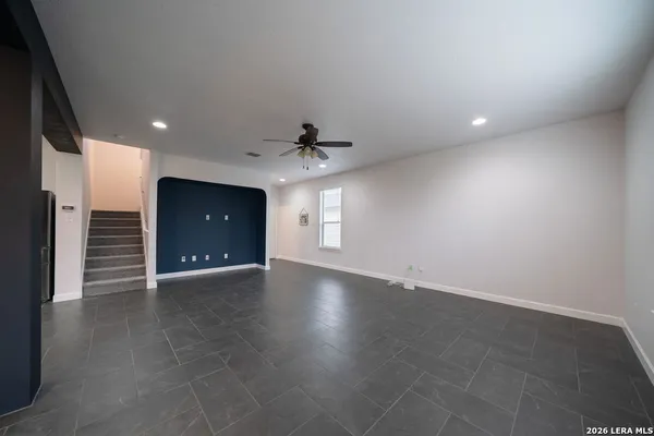 an empty room with wooden floor and a ceiling fan