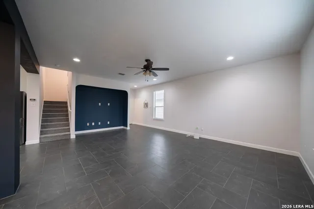an empty room with wooden floor and a ceiling fan