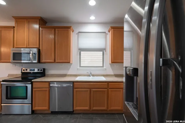 a kitchen with stainless steel appliances granite countertop a sink a stove and a refrigerator