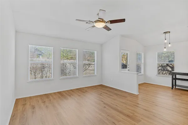 a view of empty room with wooden floor and fan