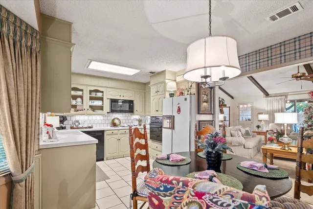a very nice looking dining room with kitchen area and a chandelier