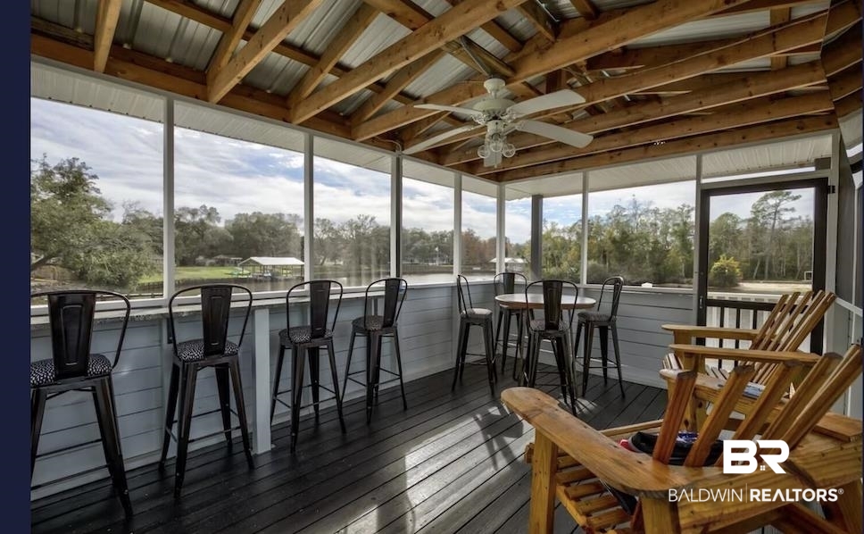 16297 Honey Road Summerdale, AL 36580 - Photo 4 of 24 Screened porch featuring exposed wood beam ceiling, metal roofing, ceiling fan, and water frontage