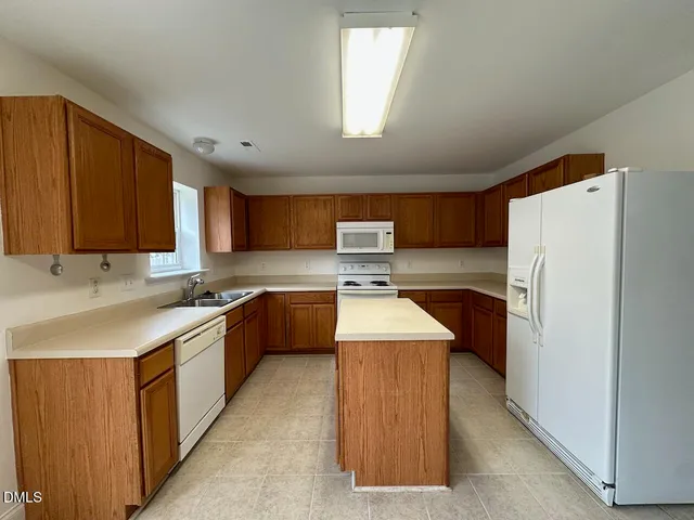 a kitchen with stainless steel appliances granite countertop a refrigerator a sink dishwasher a stove and a oven