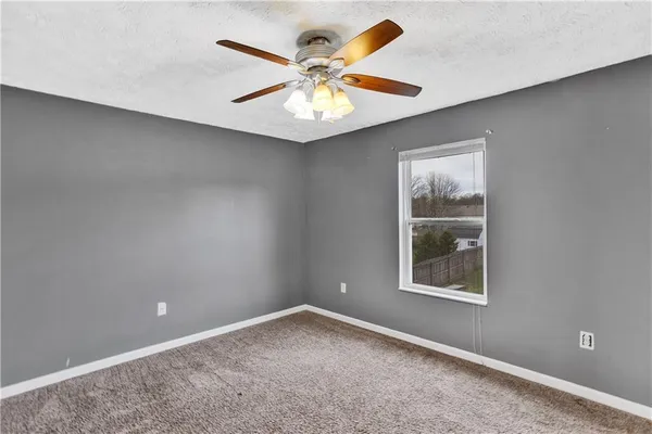 an empty room with window and ceiling fan