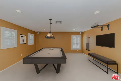 a living room with furniture pool table and a flat screen tv
