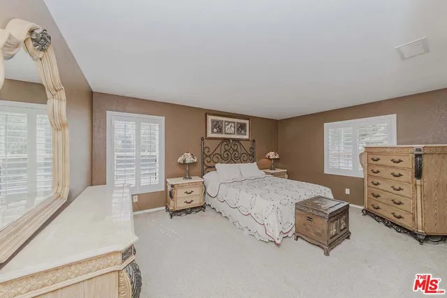a spacious bedroom with a bed and dresser