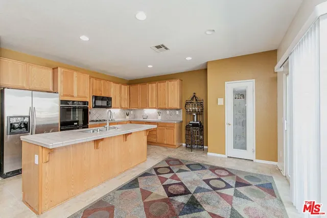 a kitchen with stainless steel appliances a sink a stove a refrigerator cabinets and a window