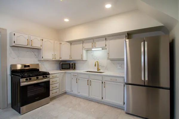 a kitchen with stainless steel appliances a refrigerator sink and white cabinets