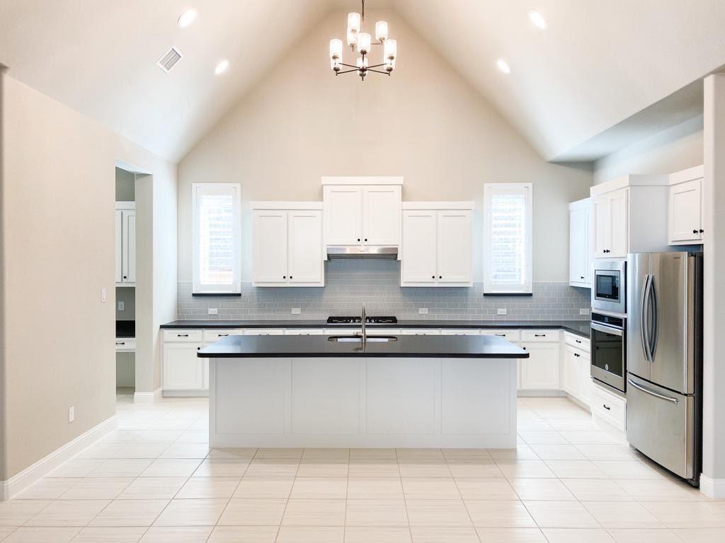 a large kitchen with stainless steel appliances granite countertop a stove a sink and a refrigerator