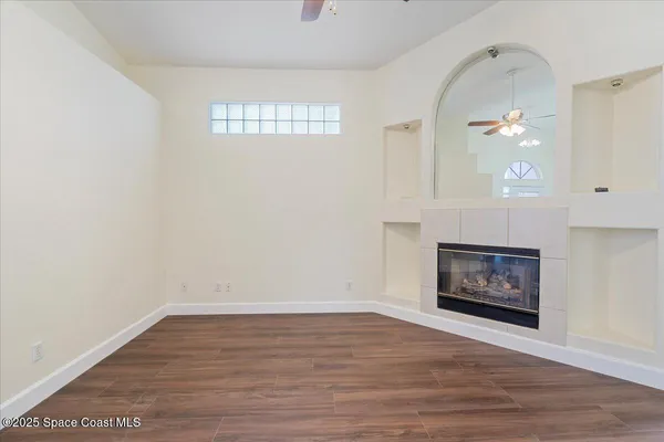 an empty room with wooden floor a fireplace and window