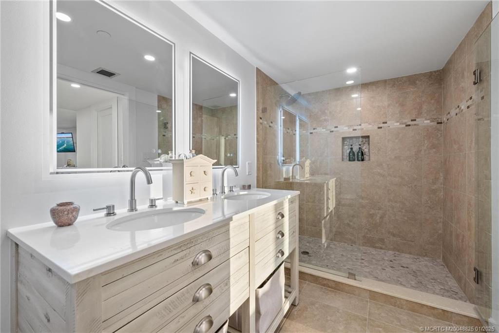 8750 South Ocean Drive, Unit 1435 Jensen Beach, FL 34957 - Photo 20 of 38 a bathroom with a granite countertop sink a mirror and shower