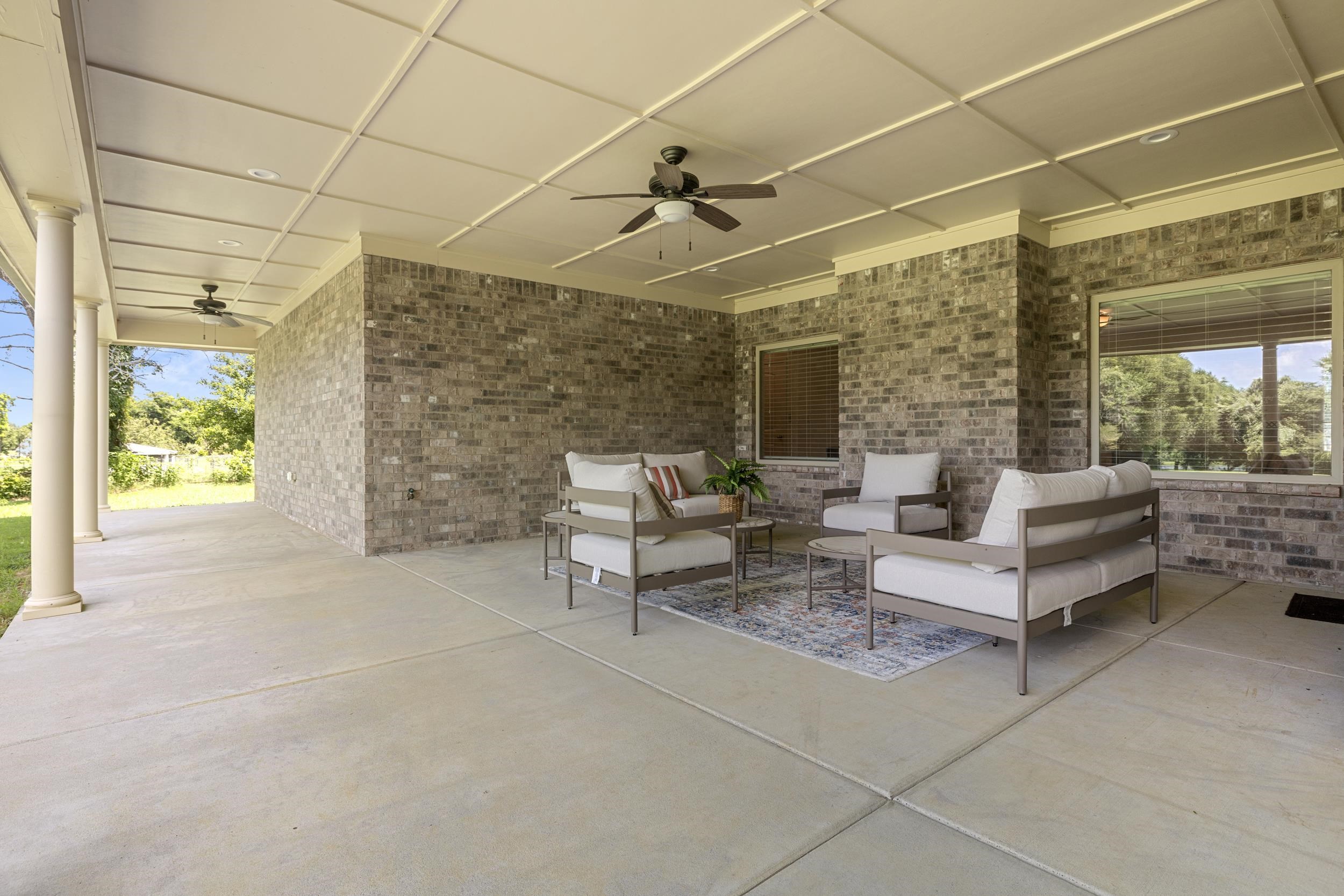 185 Belmont Road Mason, TN 38049 - Photo 11 of 38 Expansive covered patio featuring a brick exterior wall, concrete flooring, decorative ceiling panels, two ceiling fans, and multiple windows