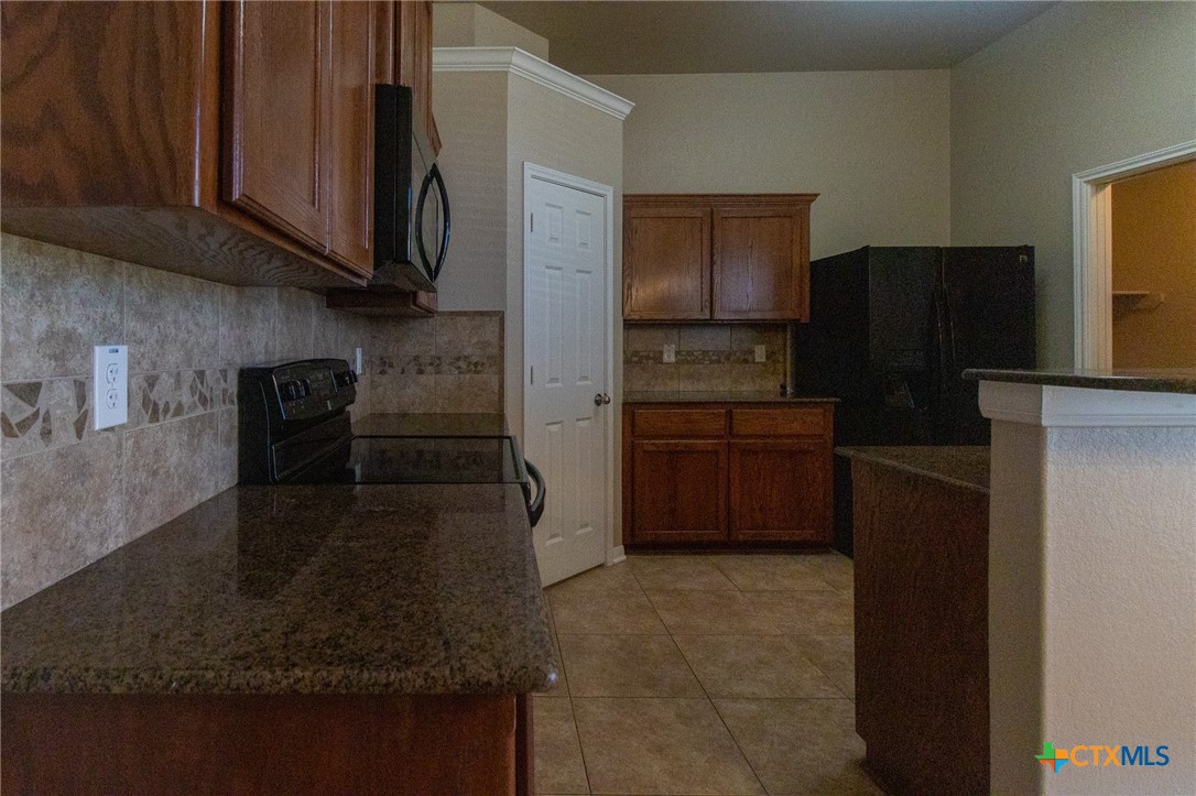217 Pointer Street Nolanville, TX 76559 - Photo 12 of 29 a kitchen with stainless steel appliances granite countertop a refrigerator and a stove