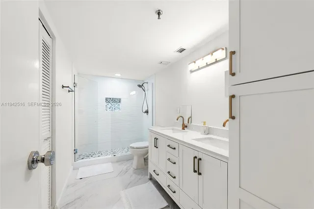 a spacious bathroom with a double vanity sink toilet mirror and shower