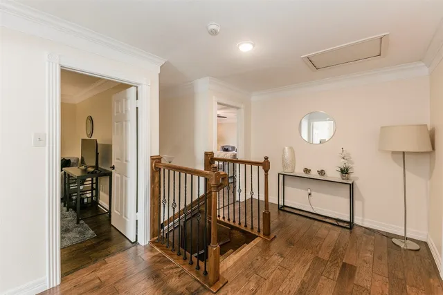 a view of a hallway to a livingroom with wooden floor and furniture