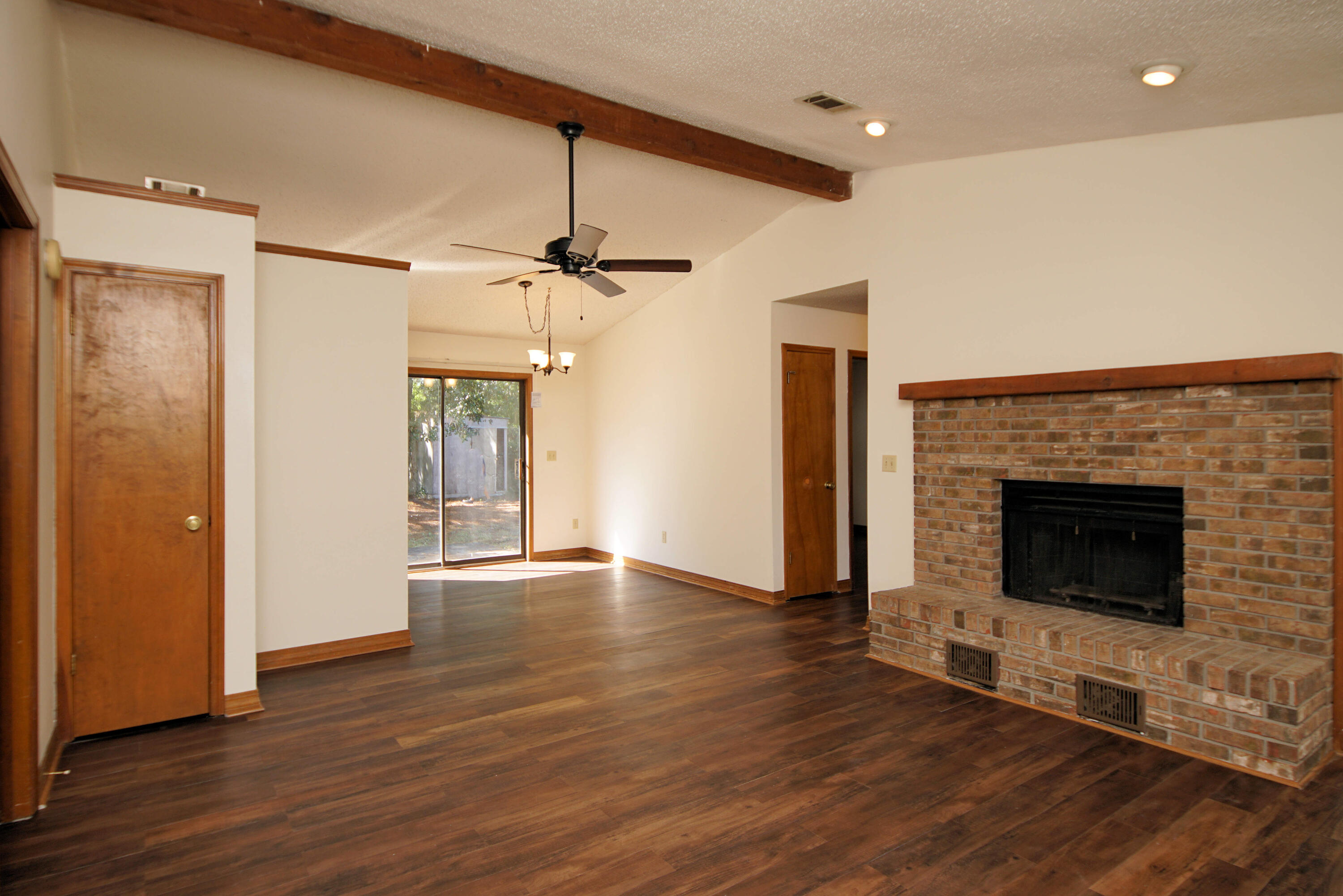 912 Nutmeg Avenue Niceville, FL 32578 - Photo 7 of 30 an empty room with wooden floor a fireplace and windows