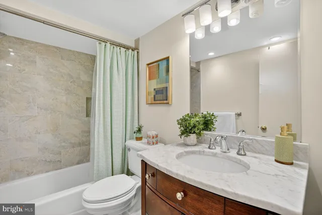 a bathroom with a granite countertop sink a toilet a mirror a vanity and shower