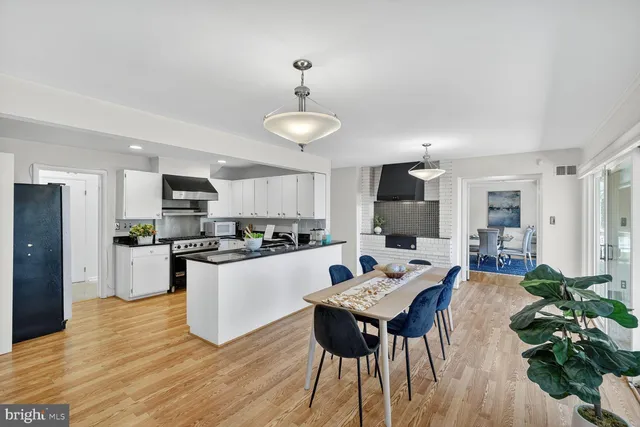 a kitchen with stainless steel appliances kitchen island granite countertop a refrigerator a stove top oven a sink dishwasher and white appliances with wooden floor