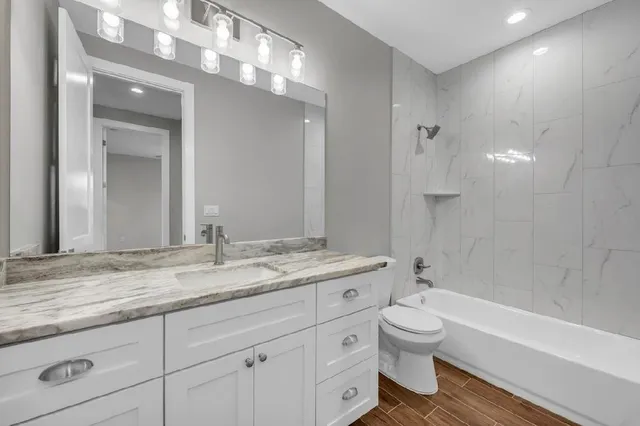 a bathroom with a granite countertop toilet a sink and a bathtub