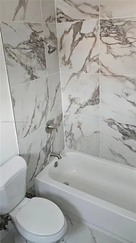 a white toilet and tub sitting next to a bathroom sink