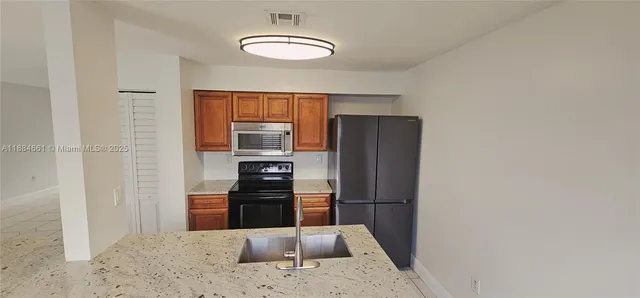 a kitchen with stainless steel appliances granite countertop a refrigerator and a sink