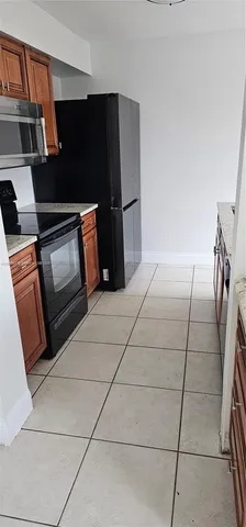 a kitchen with granite countertop a refrigerator and a stove top oven