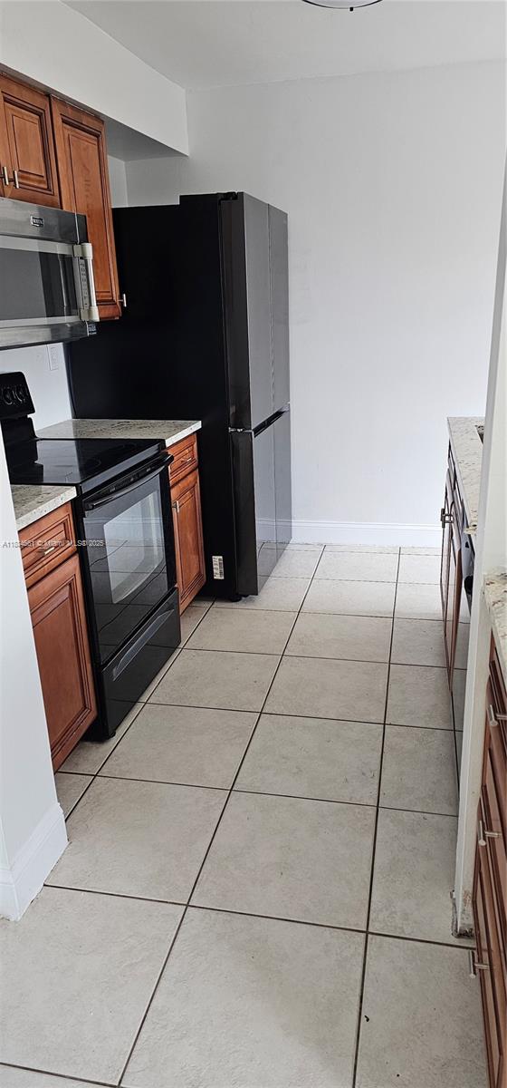 8372 Southwest 23rd Court Miramar, FL 33025 - Photo 10 of 22 a kitchen with granite countertop a refrigerator and a stove top oven