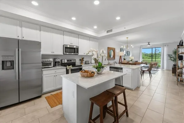 a kitchen with stainless steel appliances granite countertop a refrigerator a stove a sink a dining table and chairs