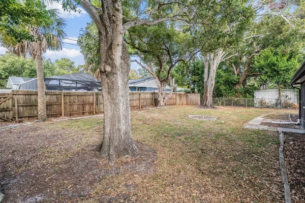 a backyard of a house with large trees and wooden fence