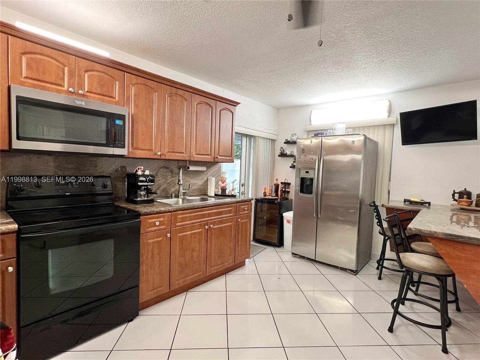 10140 Southwest 26th Terrace Miami, FL 33165 - Photo 39 of 70 a kitchen with stainless steel appliances granite countertop a stove a sink dishwasher a refrigerator and a microwave oven on the kitchen countertops