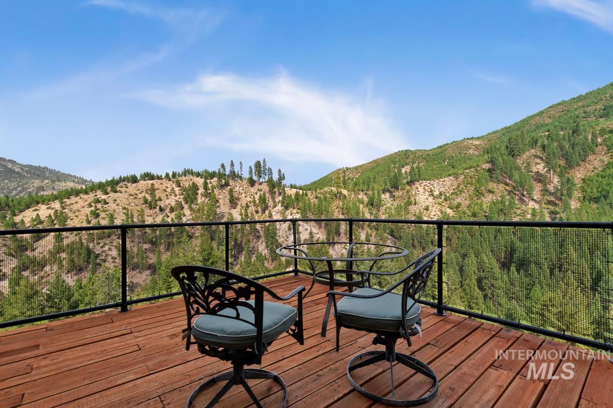 7 Scenic Rim Circle Lowman, ID 83637 - Photo 19 of 35 Outdoor deck featuring wood plank flooring, a glass panel railing, and expansive mountain scenery