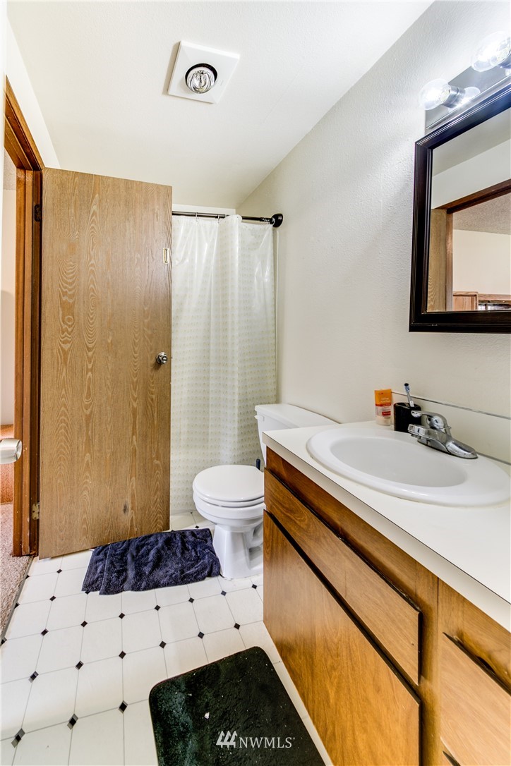 3901 Mason Loop Road, Unit AD Tacoma, WA 98409 - Photo 16 of 20 a bathroom with a sink a toilet and mirror