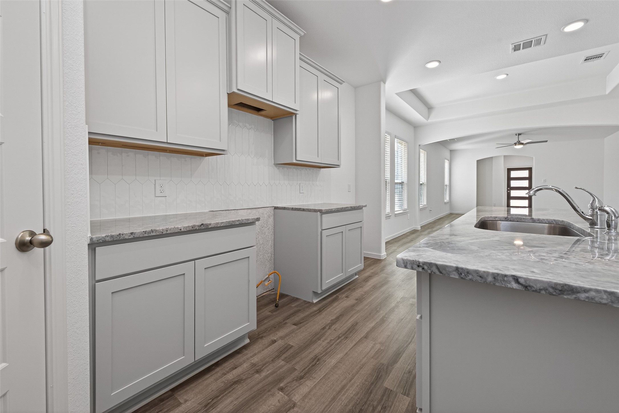 9734 Enclave Ridge Road Willis, TX 77318 - Photo 12 of 29 a kitchen with a sink dishwasher and white cabinets with wooden floor