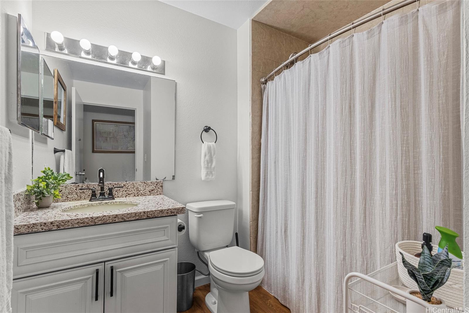 95-660 Wikao Street, Unit K304 Mililani, HI 96789 - Photo 11 of 24 a bathroom with a granite countertop sink toilet and mirror