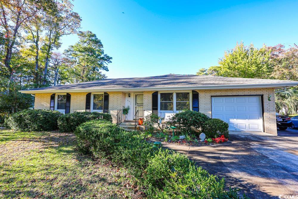 Ranch-style home featuring brick siding, a garage, a porch, and concrete driveway