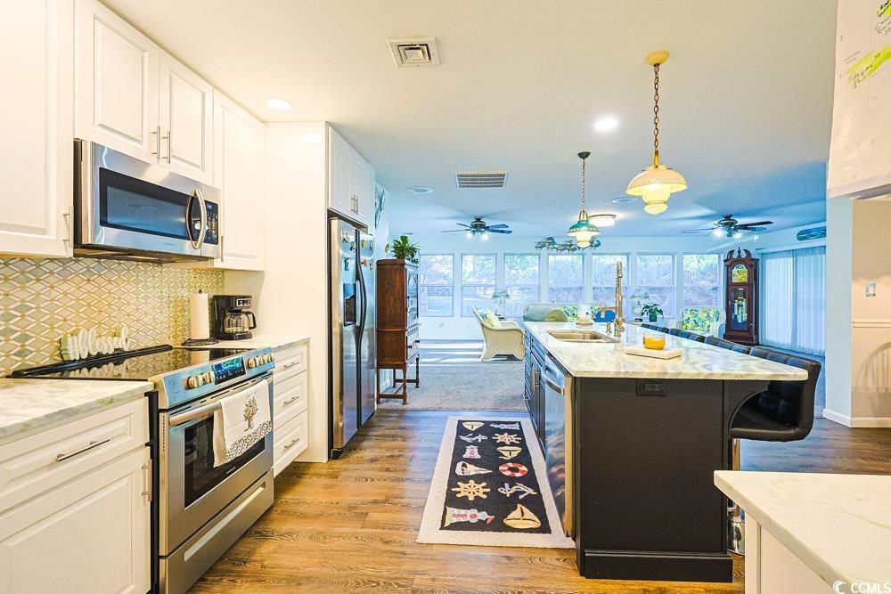 801 Talbot Circle Myrtle Beach, SC 29577 - Photo 12 of 40 Kitchen featuring white cabinetry, stainless steel appliances, decorative backsplash, hanging light fixtures, and light wood-style flooring