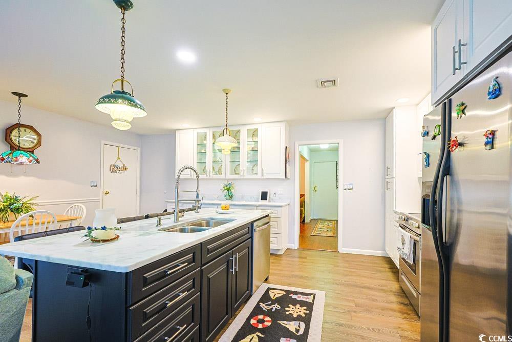 801 Talbot Circle Myrtle Beach, SC 29577 - Photo 10 of 40 Kitchen with stainless steel appliances, glass insert cabinets, white cabinets, light wood finished floors, and decorative light fixtures