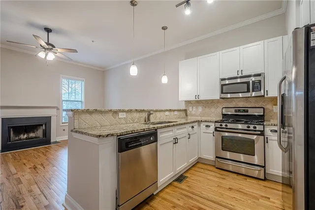 a kitchen with stainless steel appliances granite countertop a stove top oven a sink and a refrigerator