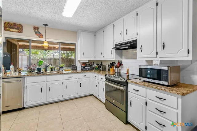a kitchen with granite countertop white cabinets stainless steel appliances and a sink