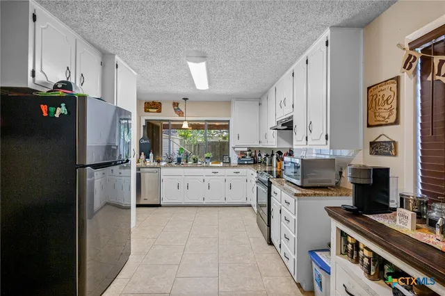 a kitchen with stainless steel appliances a refrigerator sink and white cabinets